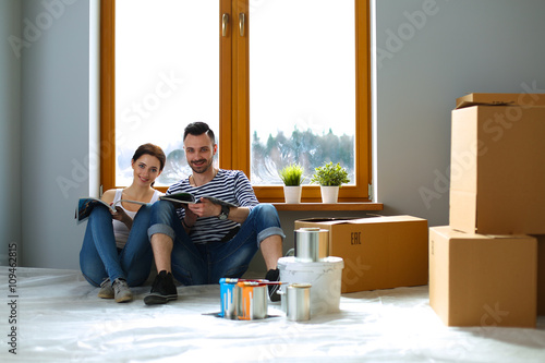 Attractive couple sitting on home floor looking at jurnal and smiling at each other. photo