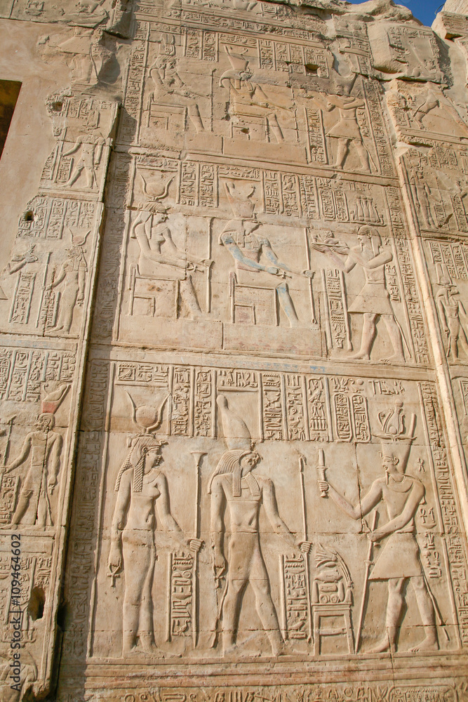 stone wall of Egyptian Kom Ombo Temple, with carving figures and hieroglyphs, with ceremony people, priest, pharaoh or king, goddess or queen, in Egypt, Africa