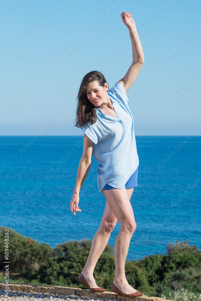 Beautiful young woman in playful mood on sunny day, with sea beh Beautiful young woman in playful mood on sunny day, with sea beh