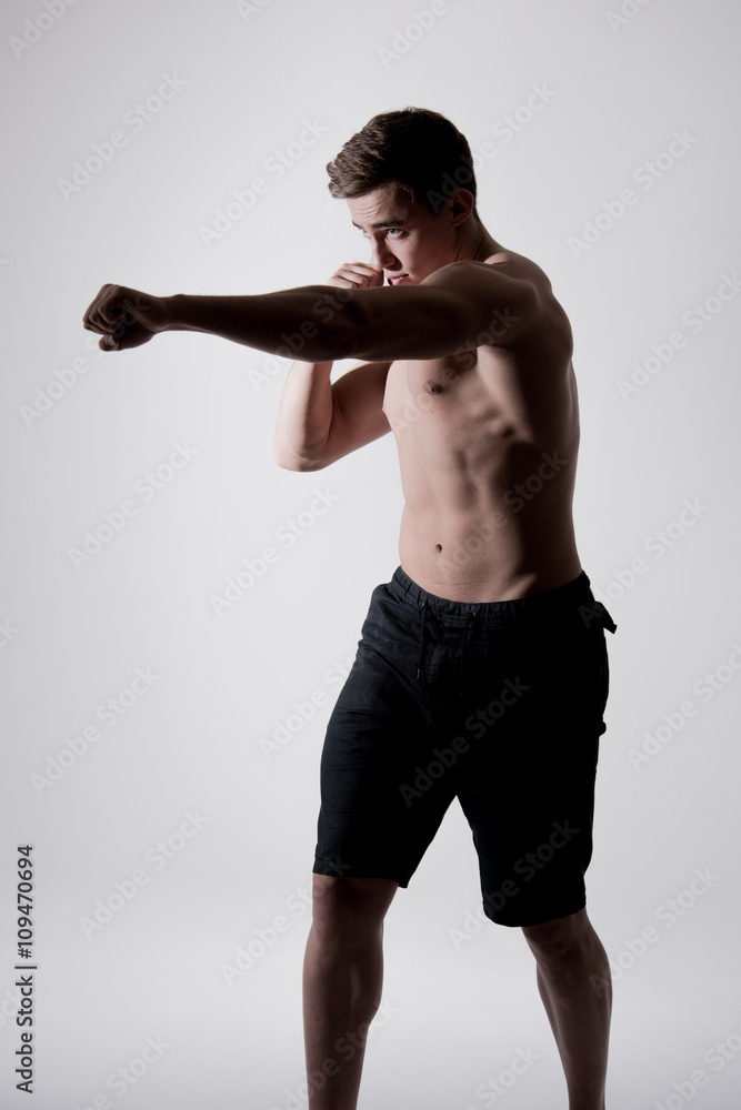 Obraz premium Portrait of powerful fighter man in fighting stance on white bac