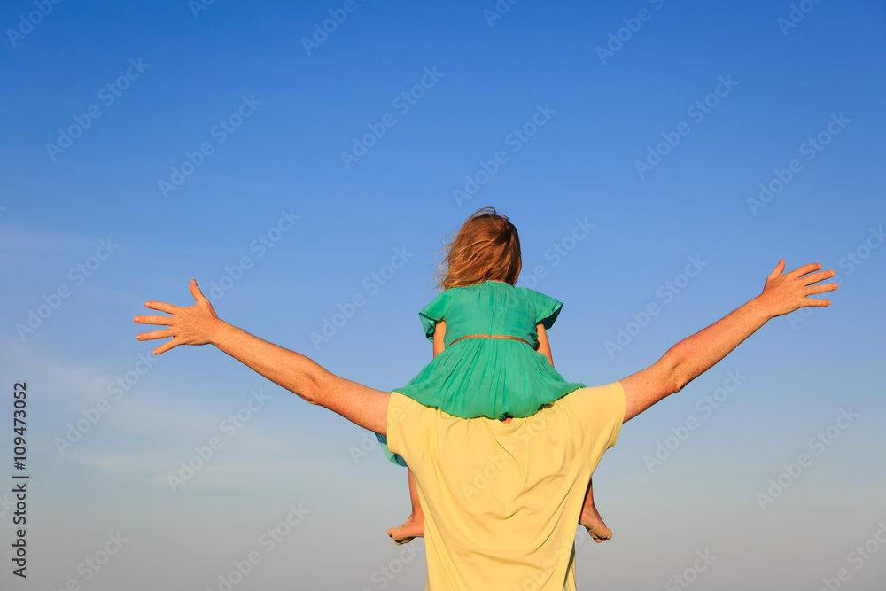father and little daughter on shoulders play at sky father and little daughter on shoulders play at sky