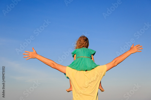 father and little daughter on shoulders play at sky