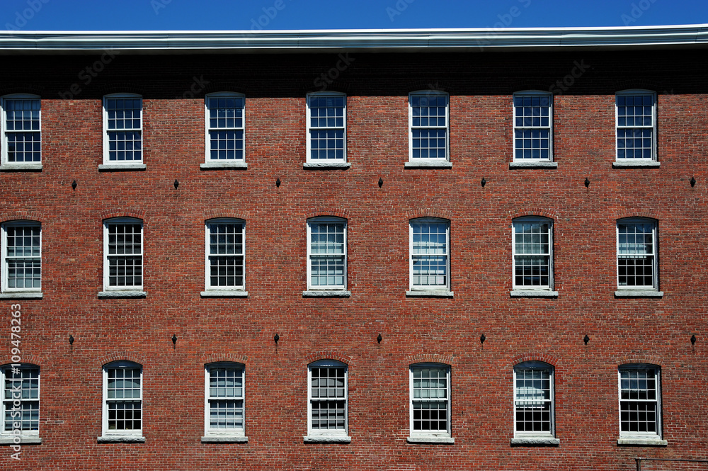 old red brick factory building exterior with many small windows, facade view