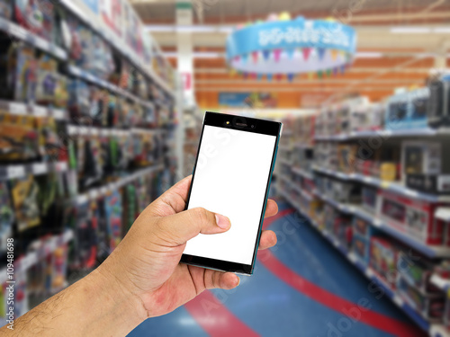 Man hand holding smart phone over blurred shopping center or super market background.