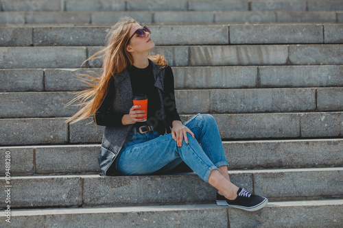 Young girl sitting on the steps with coffee in glasses.