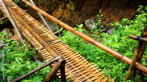 einfache geflochtene Bambusbrücke überspannt Bach im tropischen Regenwald photo