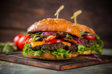 Tasty burgers on wooden table.