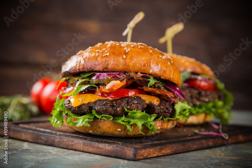 Canvas Print Tasty burgers on wooden table.