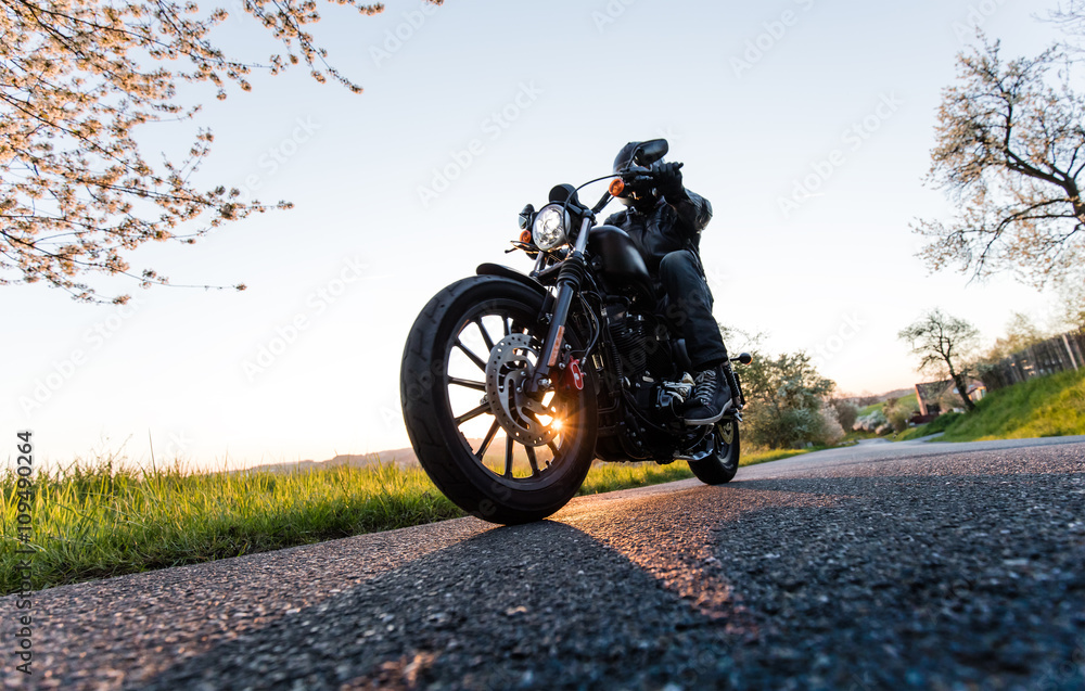 Obraz premium Siedzenie człowieka na motocyklu na drodze.