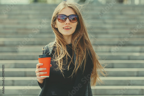Beautiful girl standing on the street with coffee.
