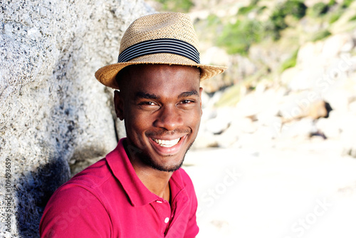 Handsome young man with hat smiling at the beach