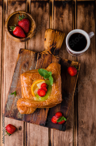 Freshly baked puff pastry with fruits and strawberries on wooden background. Selective focus. Top view