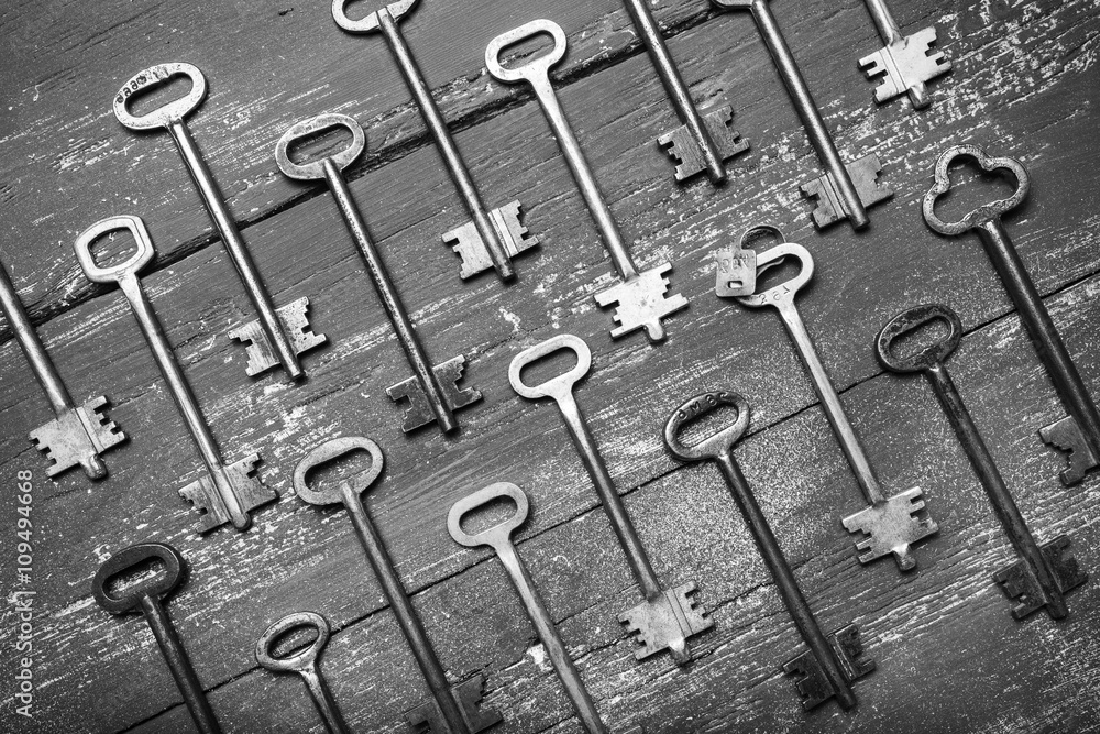 Fototapeta premium Some door keys aligned on old wooden surface, safety and security concept background