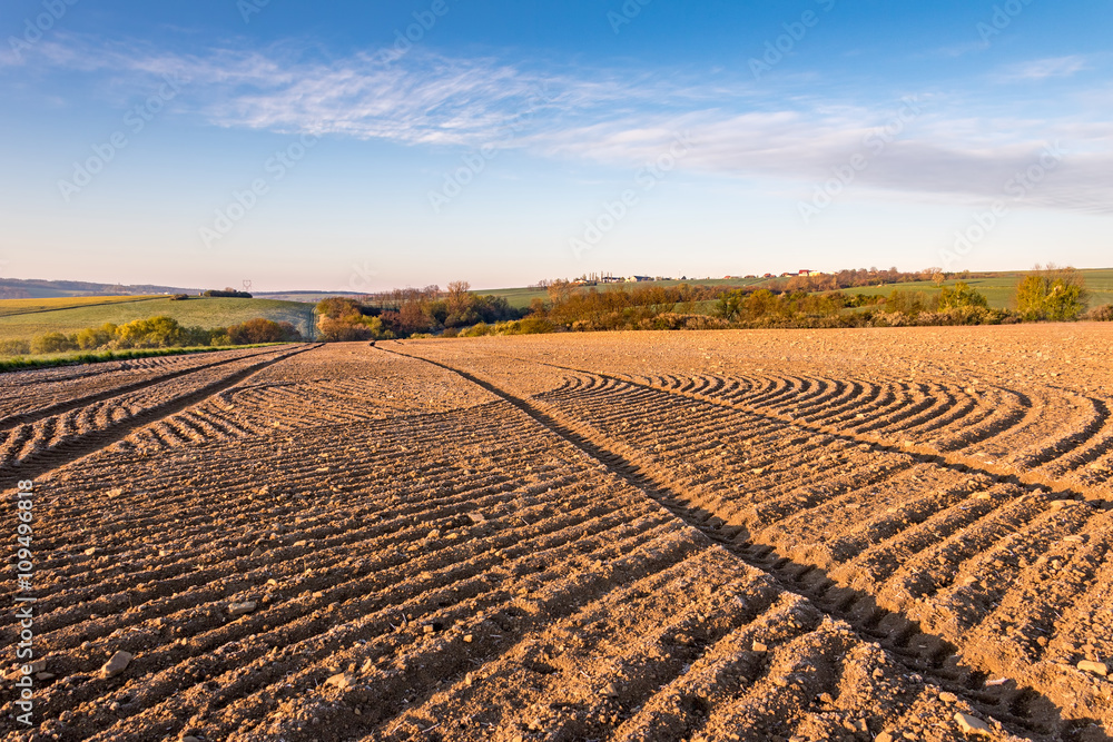 Obraz premium Spring rural countryside with ruts in plowed field