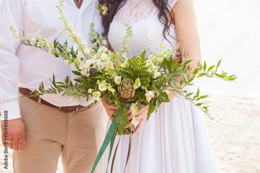 a wedding bouquet is in the hands of fiancee