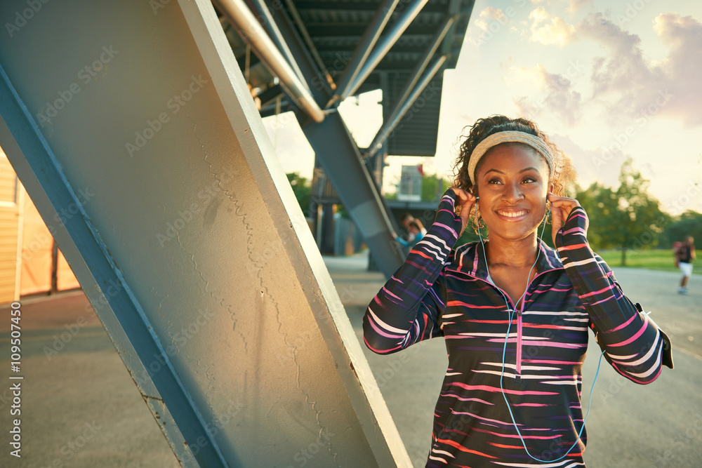 Obraz premium African american fit woman choosing music from an app for running at sunset