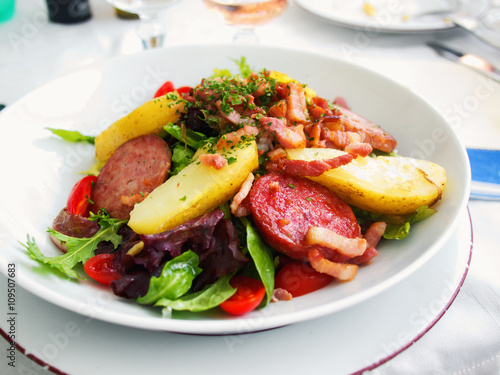 Gourmet salad with vegetables and fried ham served in a small beach restaurant in Cannes, France. Horizontal shot