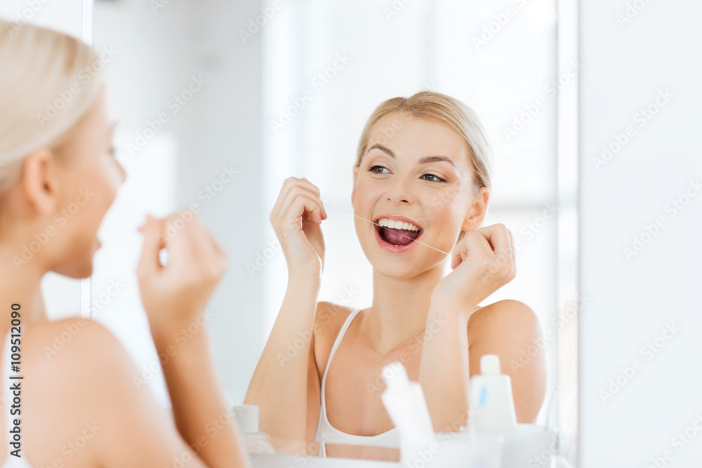 woman with dental floss cleaning teeth at bathroom woman with dental floss cleaning teeth at bathroom