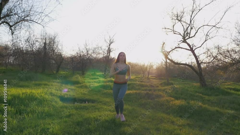 Young beautiful woman running in park at sunset, slow motion Young beautiful woman running in park at sunset, slow motion