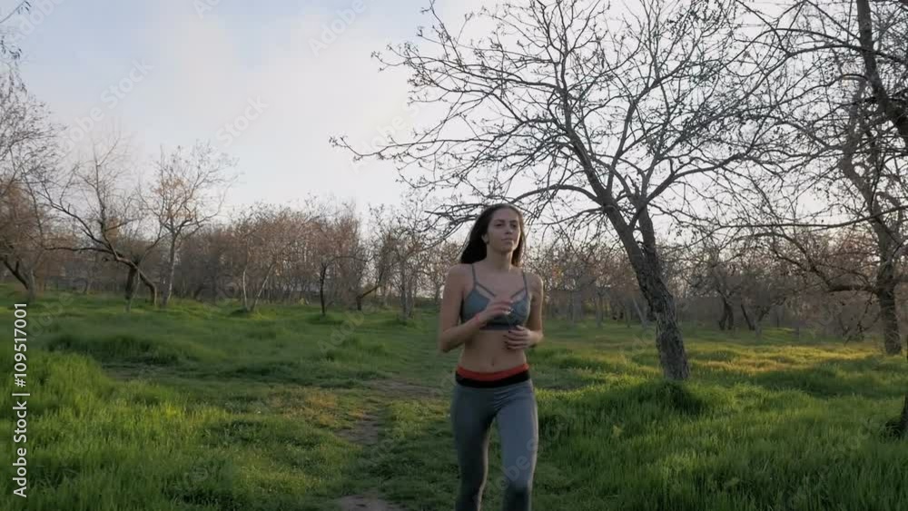 Young beautiful woman running in park at sunset, slow motion Young beautiful woman running in park at sunset, slow motion