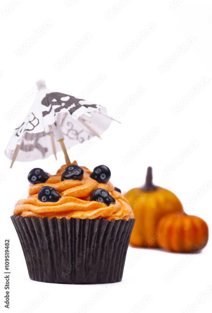 close-up shot of cupcake with skull and pumpkin in background. close-up shot of cupcake with skull and pumpkin in background.