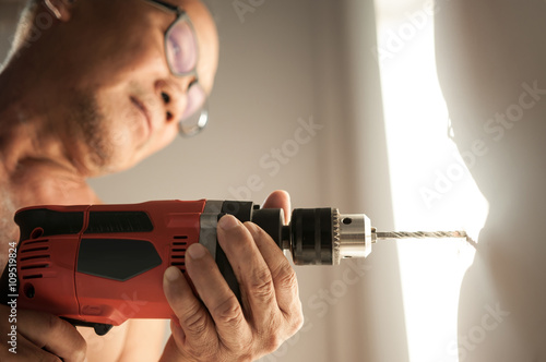 Close up drill, Old man using a drilling power tool photo