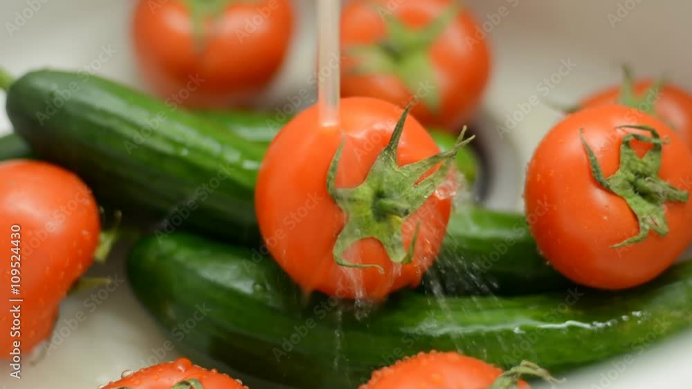 Wash vegetables in a sink. Fresh tomatoes and cucumbers under running water Wash vegetables in a sink. Fresh tomatoes and cucumbers under running water