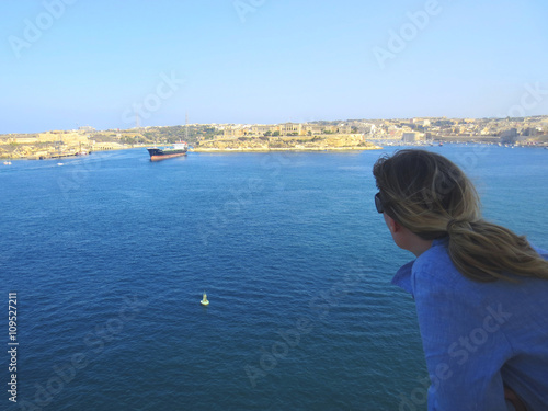 Closeup on the back hair of a girl watching the sea in Malta on vacation.Travel, outdoors.