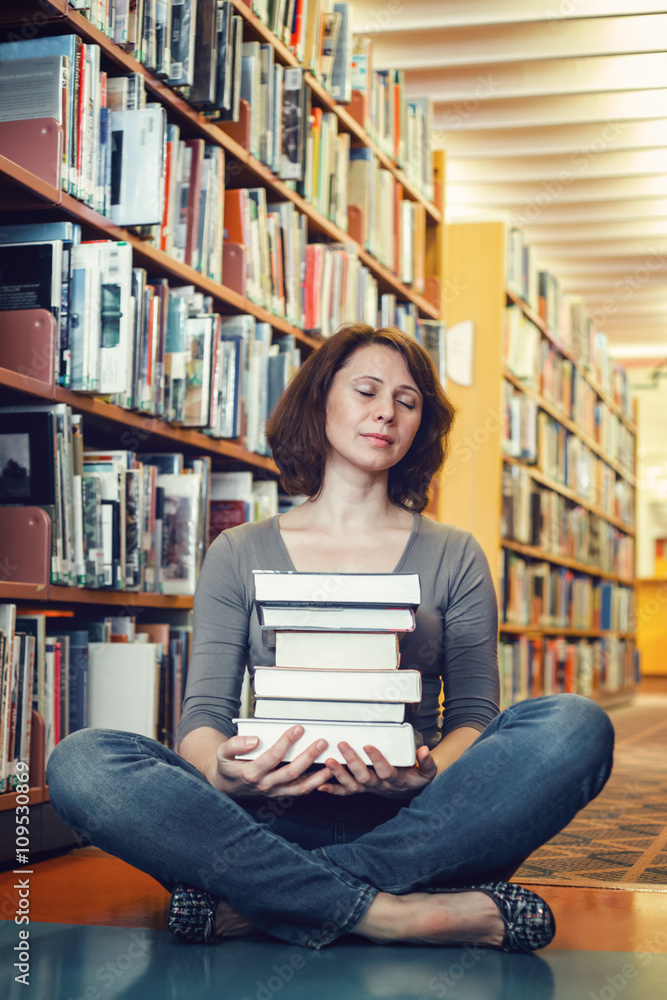 Portrait of tired middle age mature woman student sitting in library with closed eyes meditating, sleeping, teacher librarian profession, back to school concept Portrait of tired middle age mature woman student sitting in library with closed eyes meditating, sleeping, teacher librarian profession, back to school concept