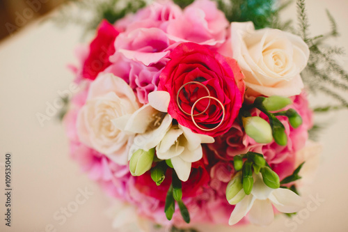 Two Golden wedding rings on bride s bouquet of roses