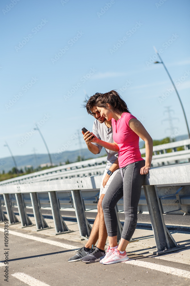 Young sport couple looking at phone after jogging.
