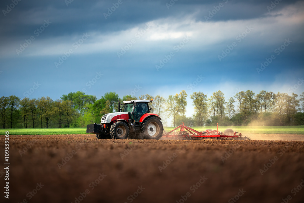 Farmer in tractor preparing land with seedbed cultivator Farmer in tractor preparing land with seedbed cultivator