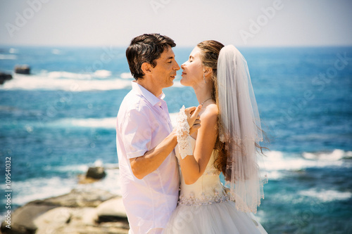 Elegant smiling bride and groom walking on the beach, kissing, wedding ceremony, Mediterranean Sea.  © siyatsky