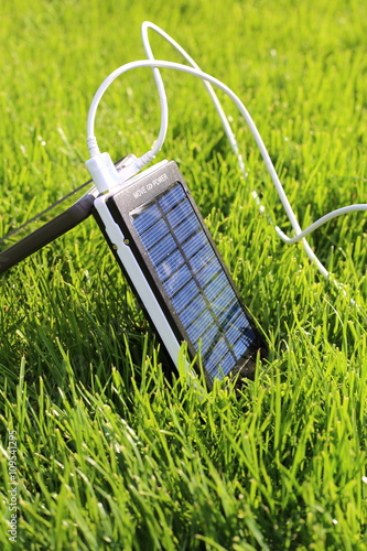 solar powerbank smartphone charging on a green grass