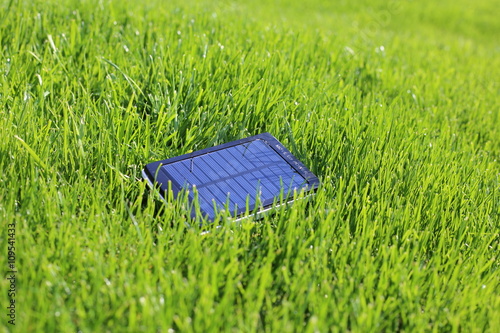 solar powerbank smartphone charging on a green grass