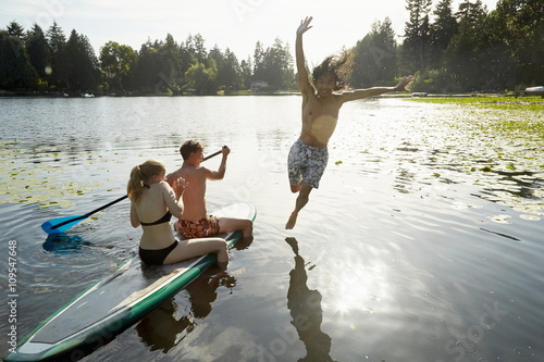 Couple paddling boat, man jumping into lake, Seattle, Washington, USA