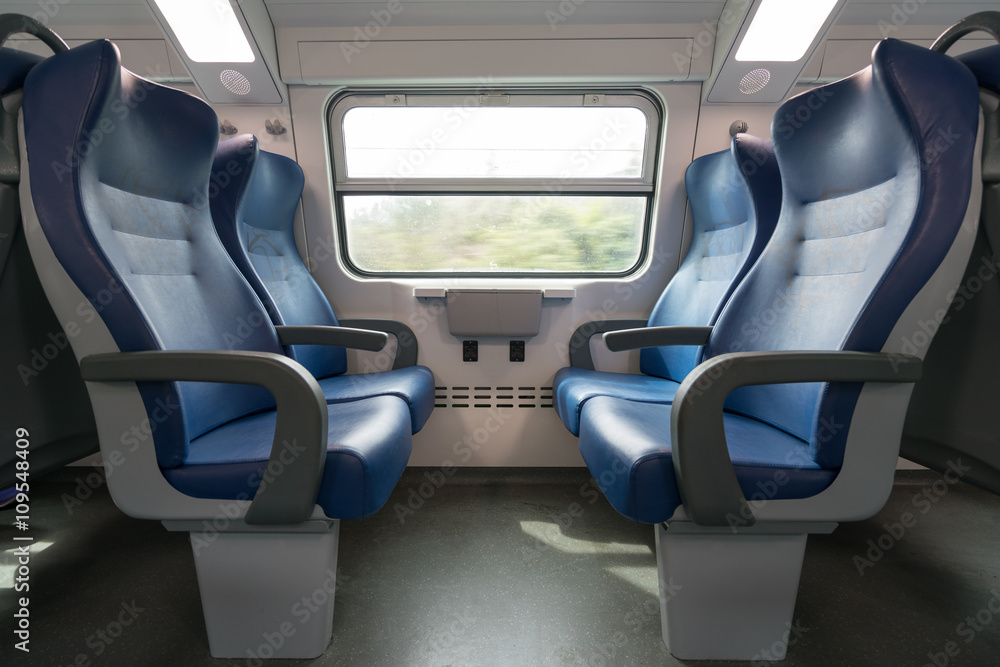 Naklejka premium Four empty blue seats facing each other in modern European train. Railroad trip travel or transportation concept