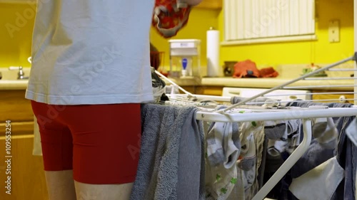 Man standing in his kitchen hanging clothes out of the washer to air dry. photo