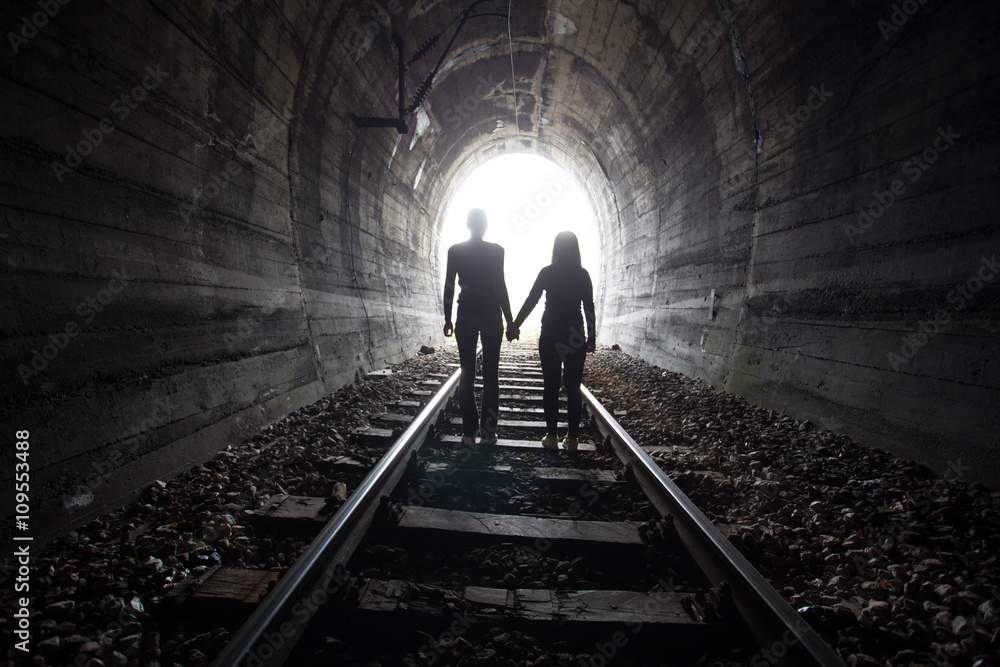 Couple walking together through a railway tunnel