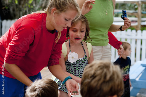 Young woman holding sea creature, showing children