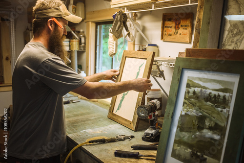 Artist working in workshop, framing artwork