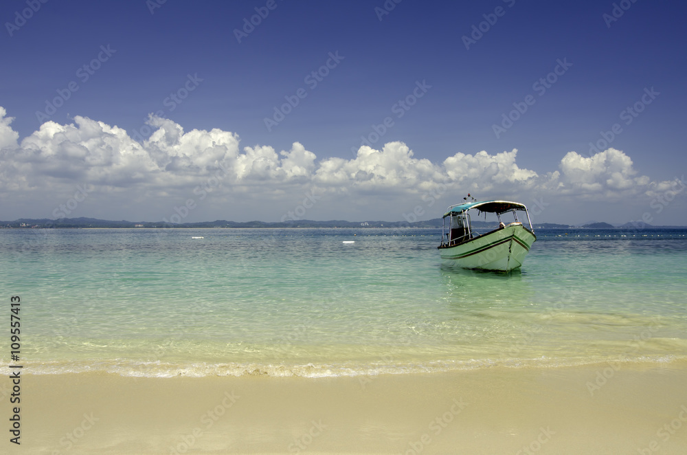 Beautiful tropical beach at Kapas Island, Malaysia. tourist boat anchored with blue sky background and crystal clear blue sea water.copy space to the left