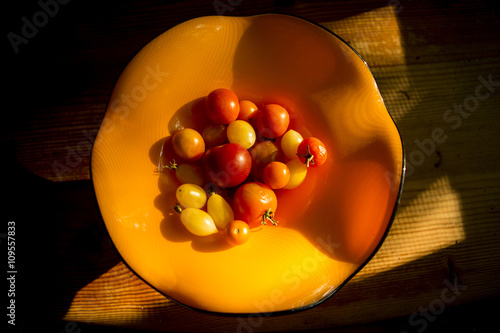 Overhead view of tomatoes in orange bowl on wood table photo