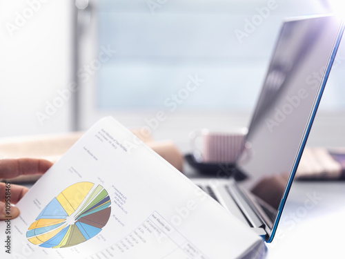 Man reviewing financial affairs using investment statement and laptop