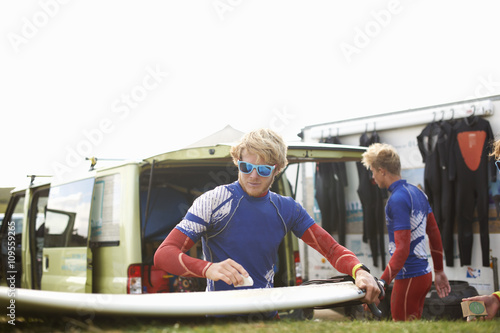 Male surfer waxing surfboard photo