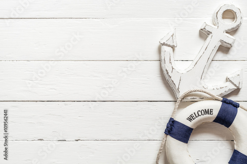 Anchor and lifebuoy on white wood table