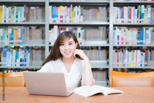 young beautiful asian girl with laptop in school library