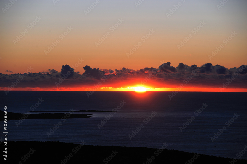 sunrise from horizon ocean surface with island silhouette as front view sunrise from horizon ocean surface with island silhouette as front view
