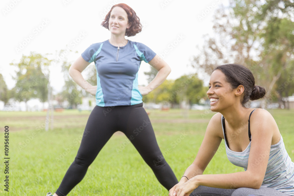 Young women wearing sports clothing in field stretching, looking away smiling Young women wearing sports clothing in field stretching, looking away smiling