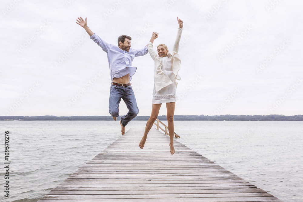 Mature couple jumping for joy on pier Mature couple jumping for joy on pier